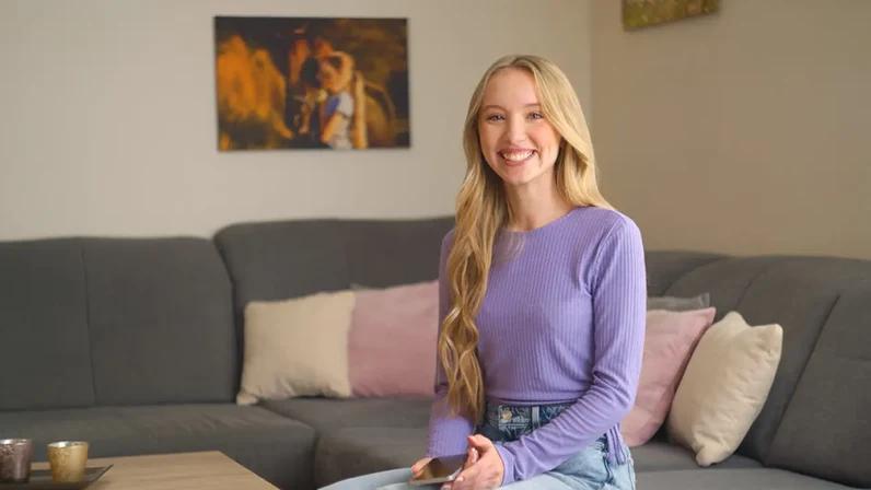 junge frau auf couch mit handy lacht | 1&1 junge frau auf couch mit handy lacht