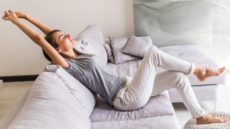 person sitzt auf sofa und streckt sich | 1&1 person sitzt auf sofa und streckt sich